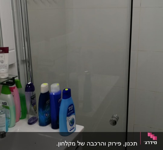 מקלחון זכוכית עם ידית מתכת בחדר אמבטיה